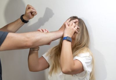 A man mistreating a woman who grabs her in the neck and face